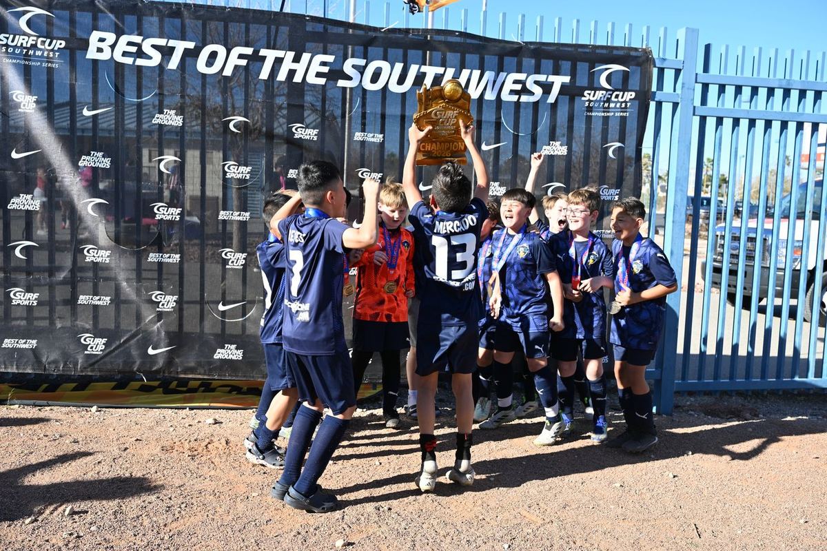 Storm boys lifting the Surf Cup 2026 trophy in front of the Best of the Southwest banner